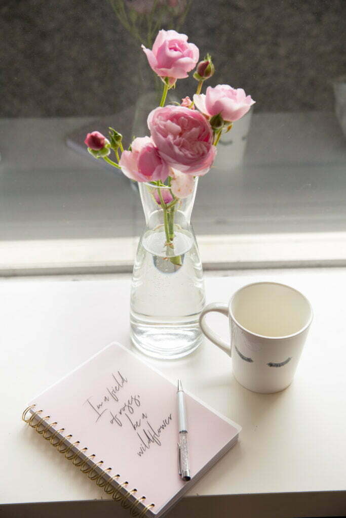 Glass vase with pink flowers and dream journal. Writing our dreams in a journal is the first step of dream interpretation.