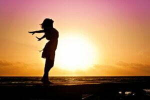 Woman with open arms to the sun symbolizes awakening with dreamwork.