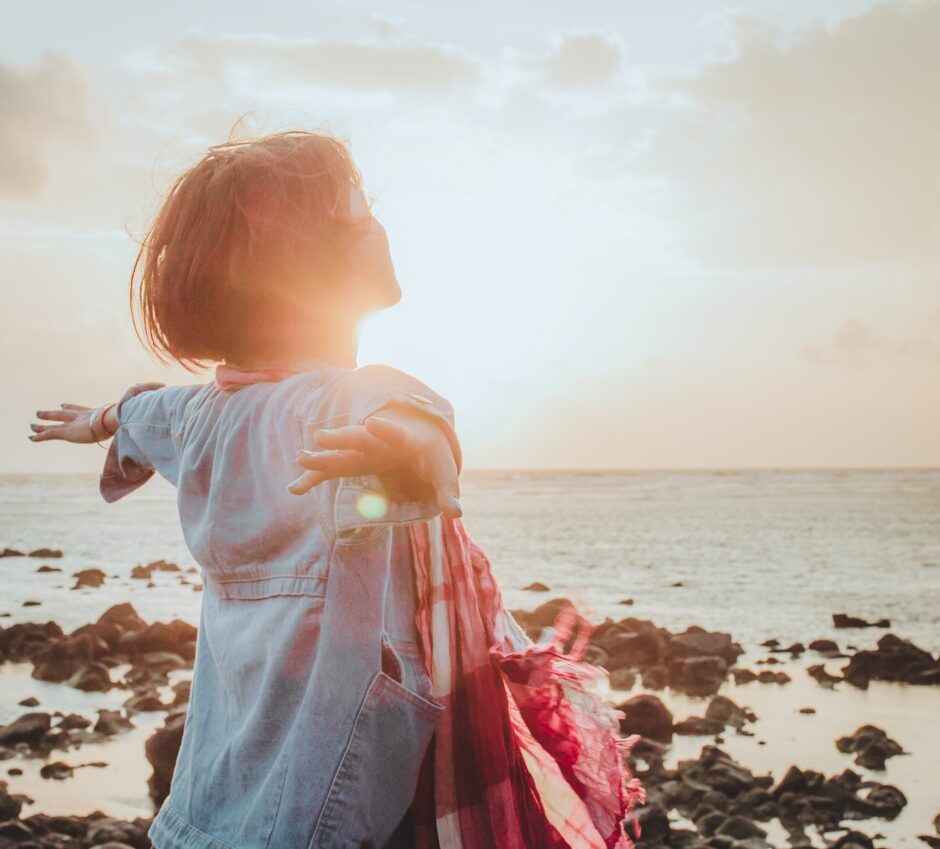 Girl with open heart to sun and ocean