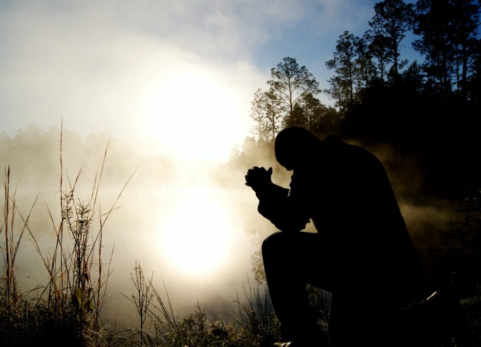 Man praying in the light of dawn