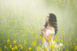 Young woman praying in a field of flowers. Prayer is one of many essential spiritual practices.