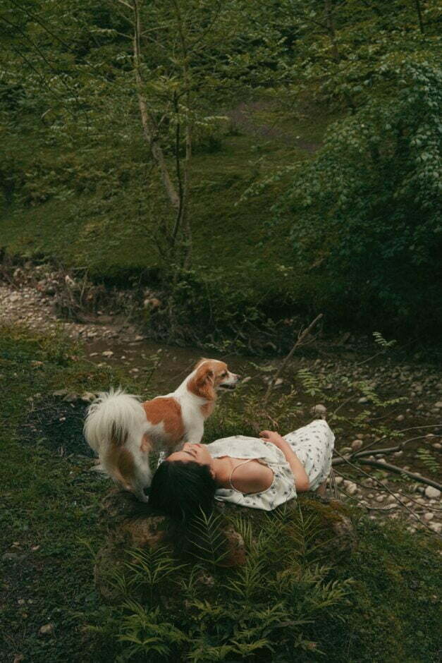 Woman relaxing in forest with dog reducing stress-eating.