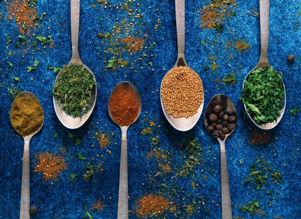 Herbs in spoons on blue background