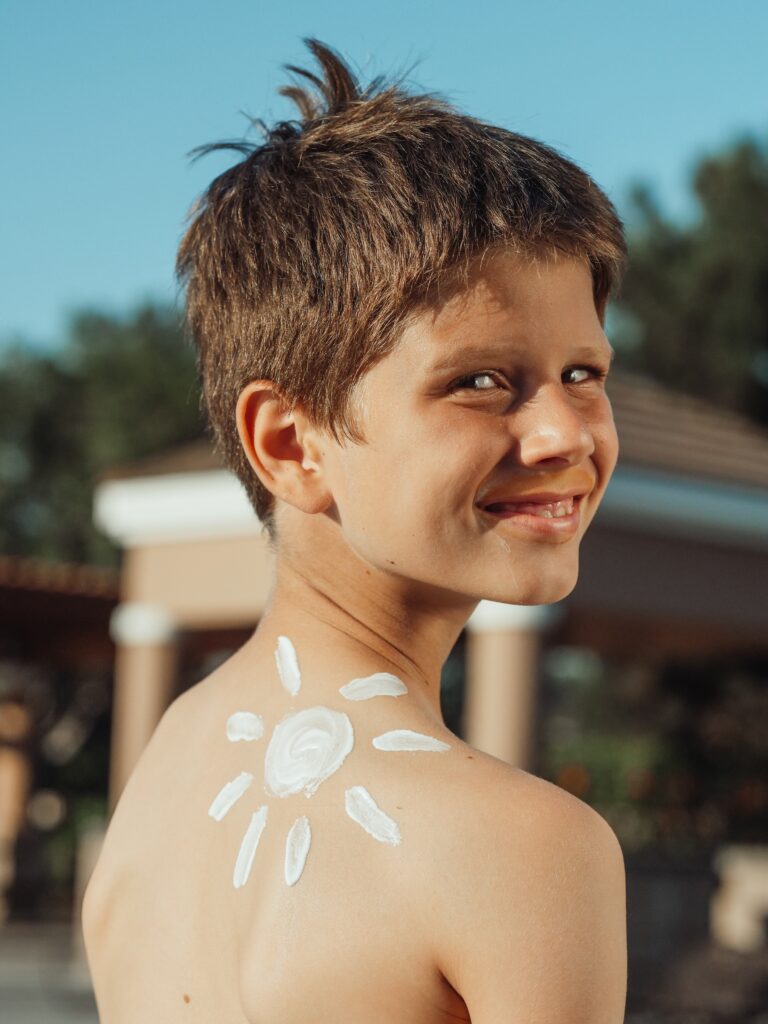 Smiling boy with natural sunscreen, another integrative health product, on his upper back in shape of a sun