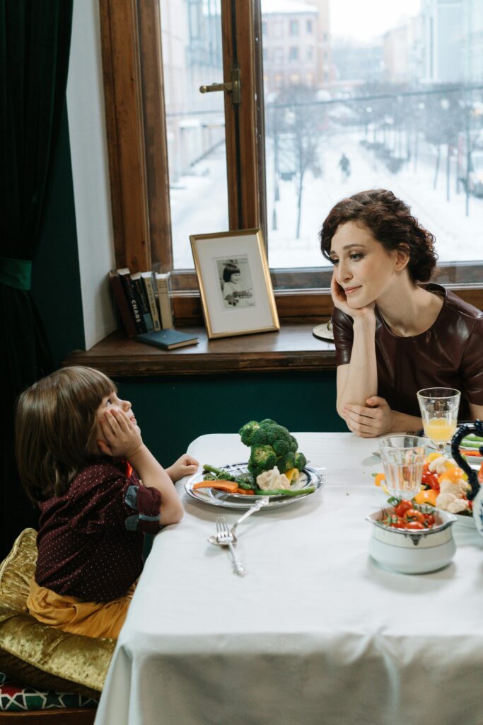 Daughter mirroring her mother at mealtime. Holistic nutrition starts with healthy mothering.