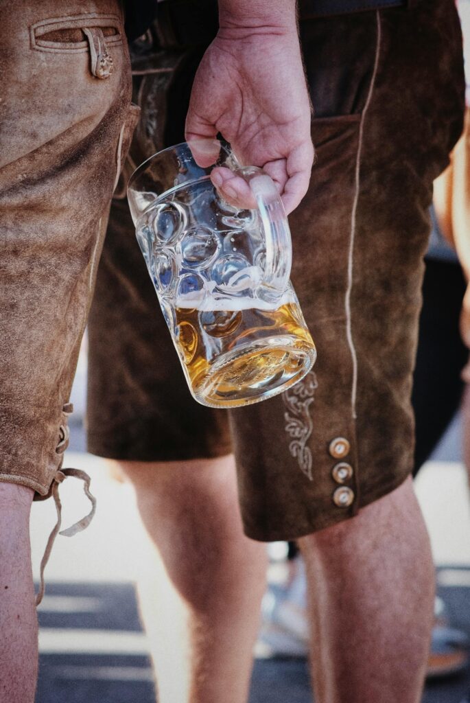 Man holding beer in a glass beside another man. Alcohol depletes nutrients in men and women and children.